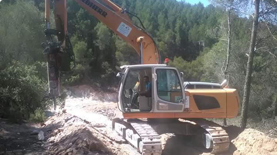 Retroexacavadora de la empresa Horcipar en funcionamiento en un camino de tierra.